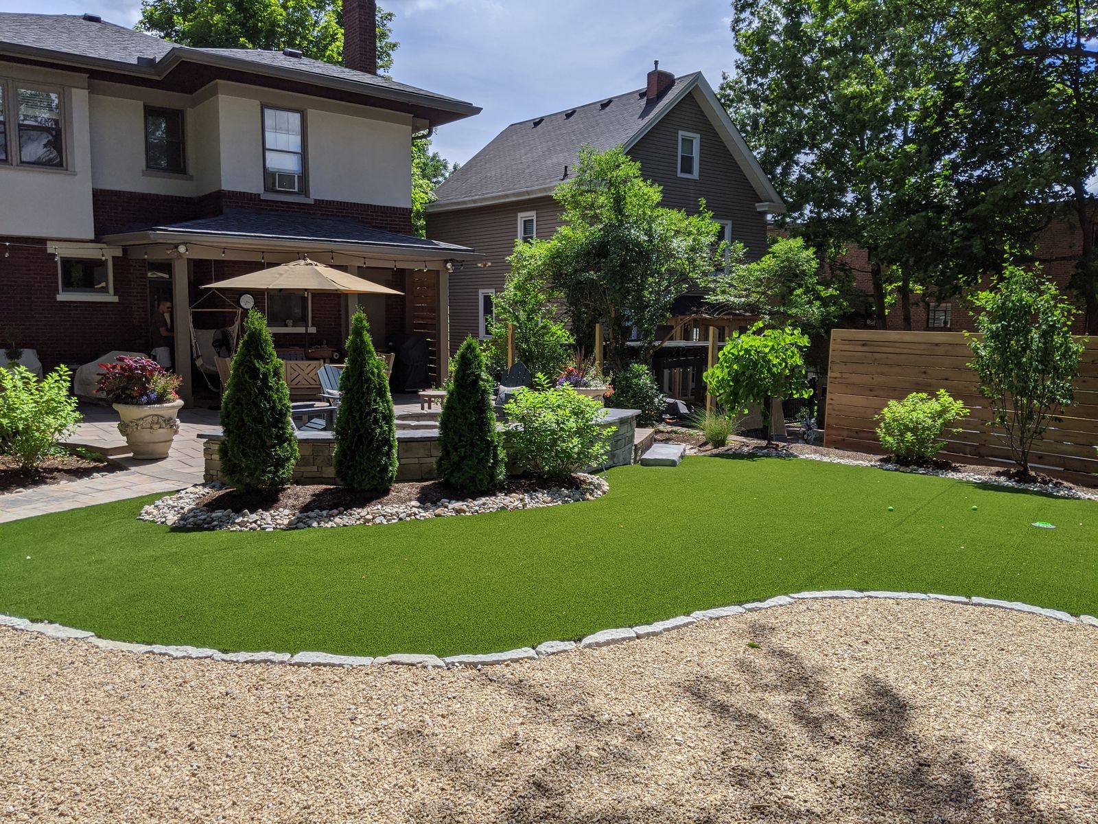 Backyard lawn and paver patio beside a covered porch