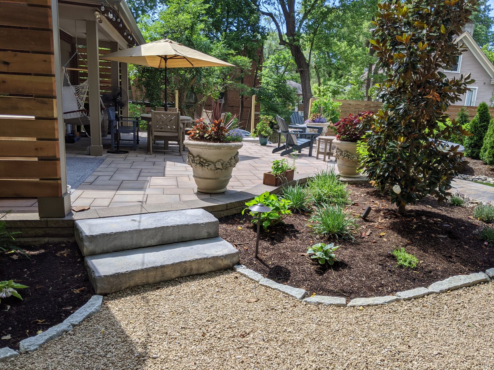 Stone steps rising to a paver dining terrace with planters
