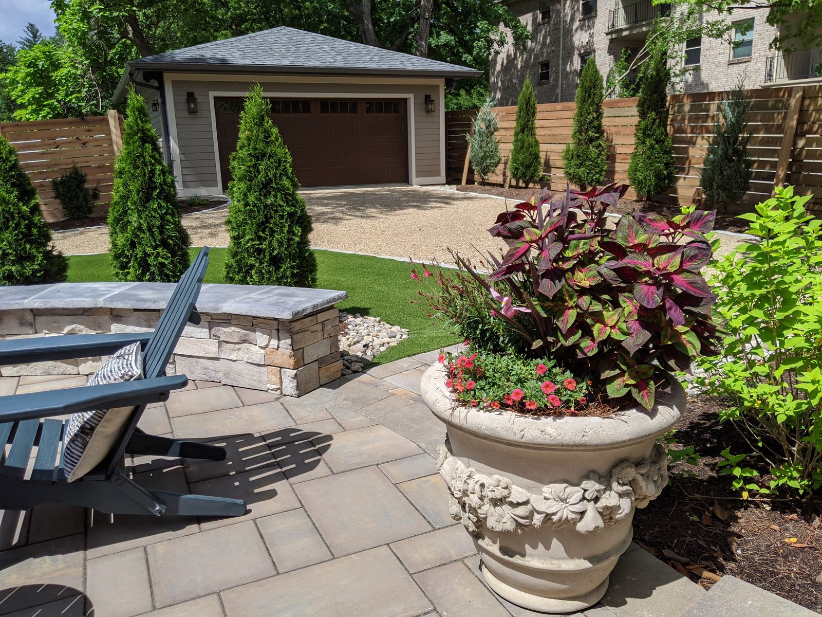 Paver patio with decorative planter and view of detached garage