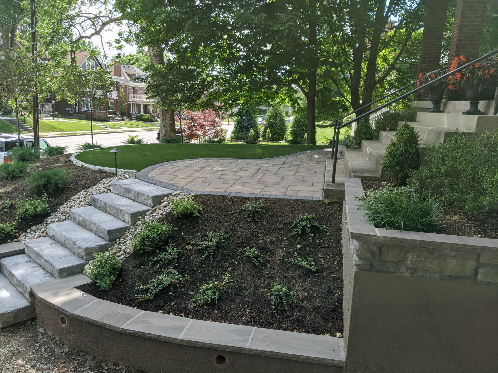 Curved paver walk with tiered planting beds and low stone walls