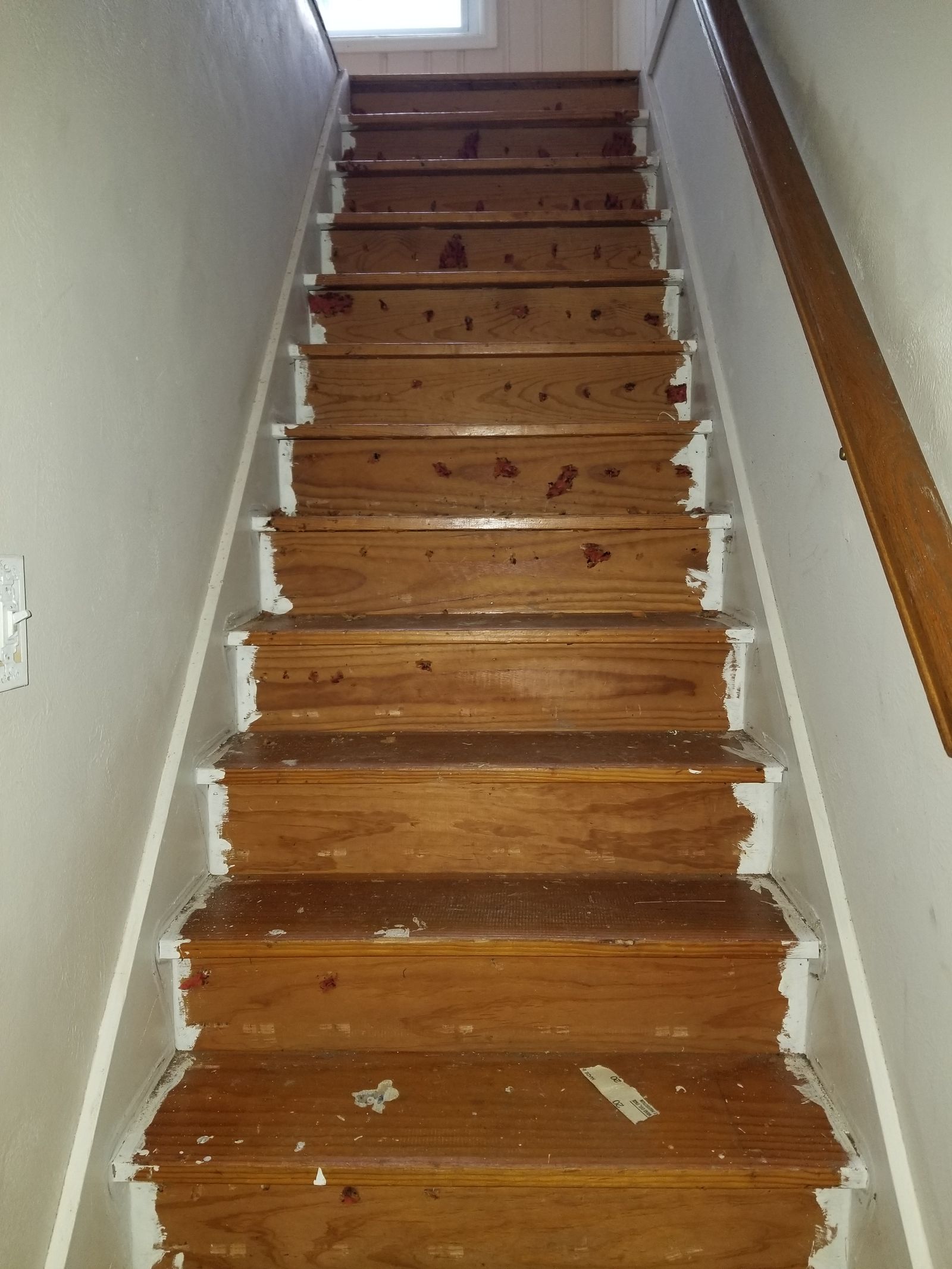 Worn wooden staircase with chipped paint, stained treads, and damaged risers before refinishing