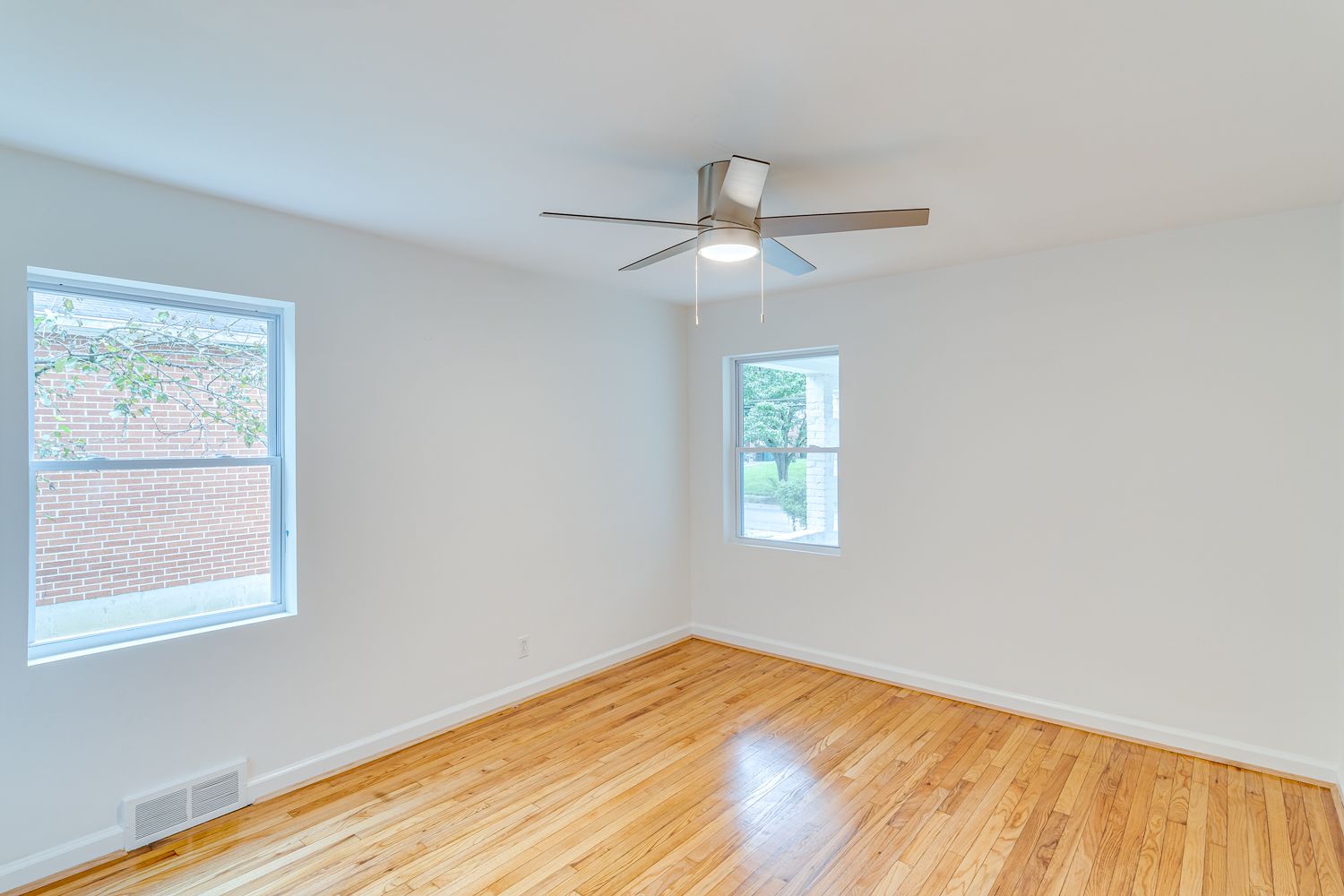 Bright bedroom with hardwood floors and ceiling fan