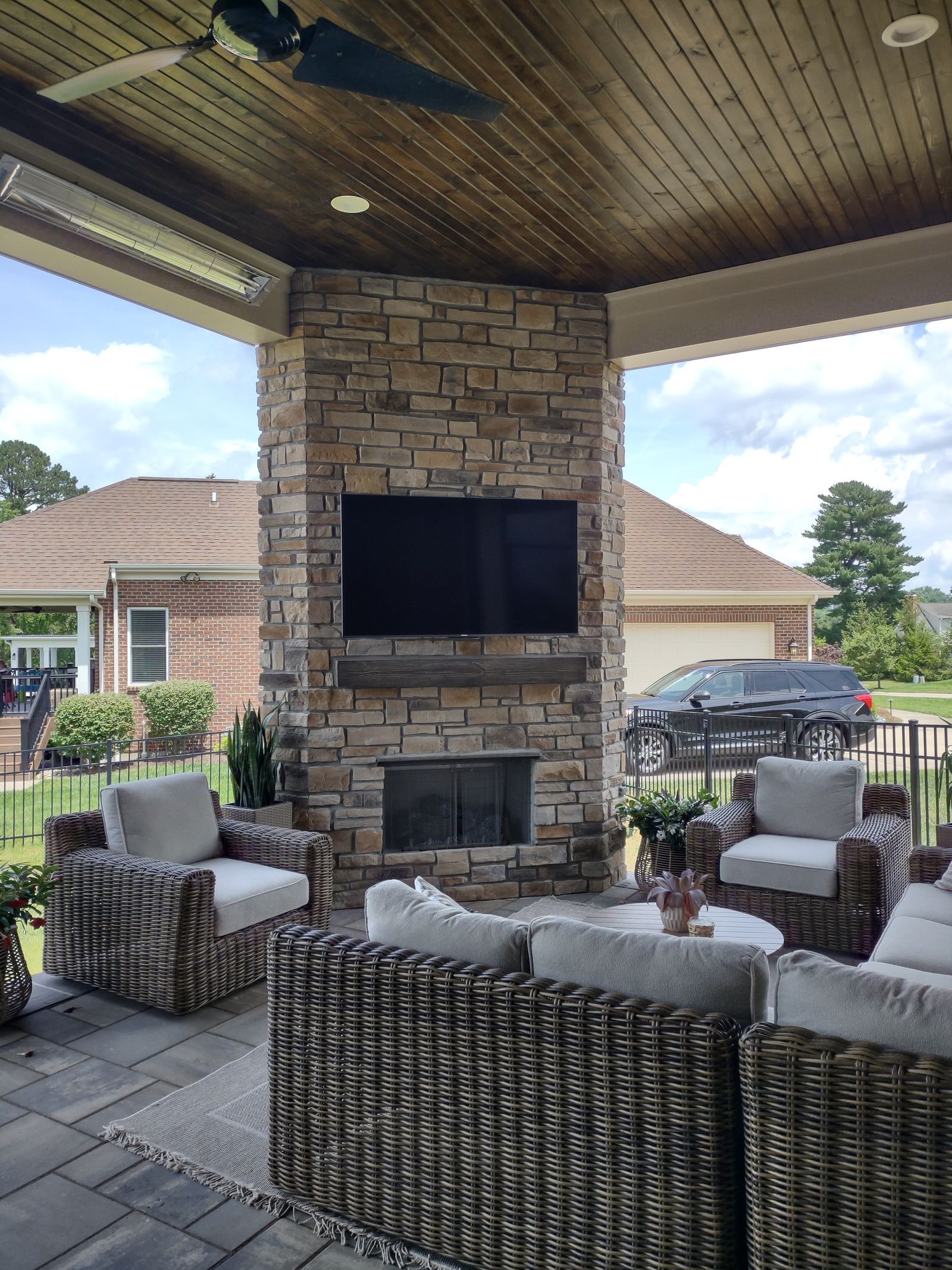 Covered porch lounge with a wood ceiling and fireplace