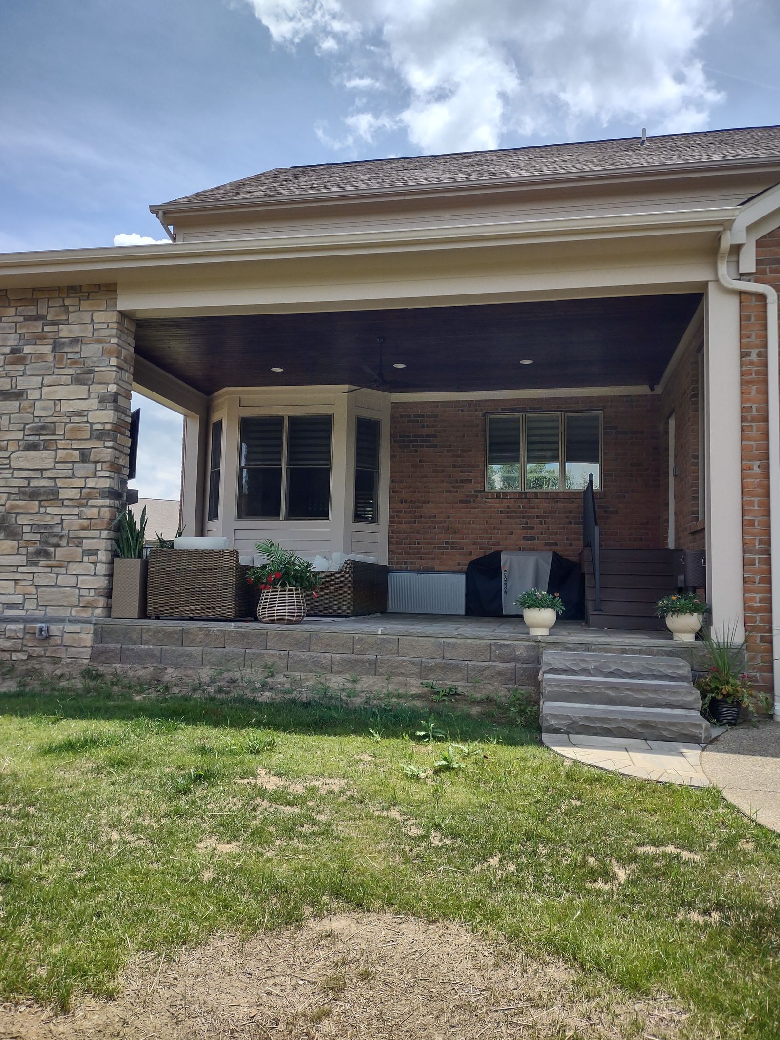 Covered back porch with stone columns, vaulted wood ceiling and wide entry steps