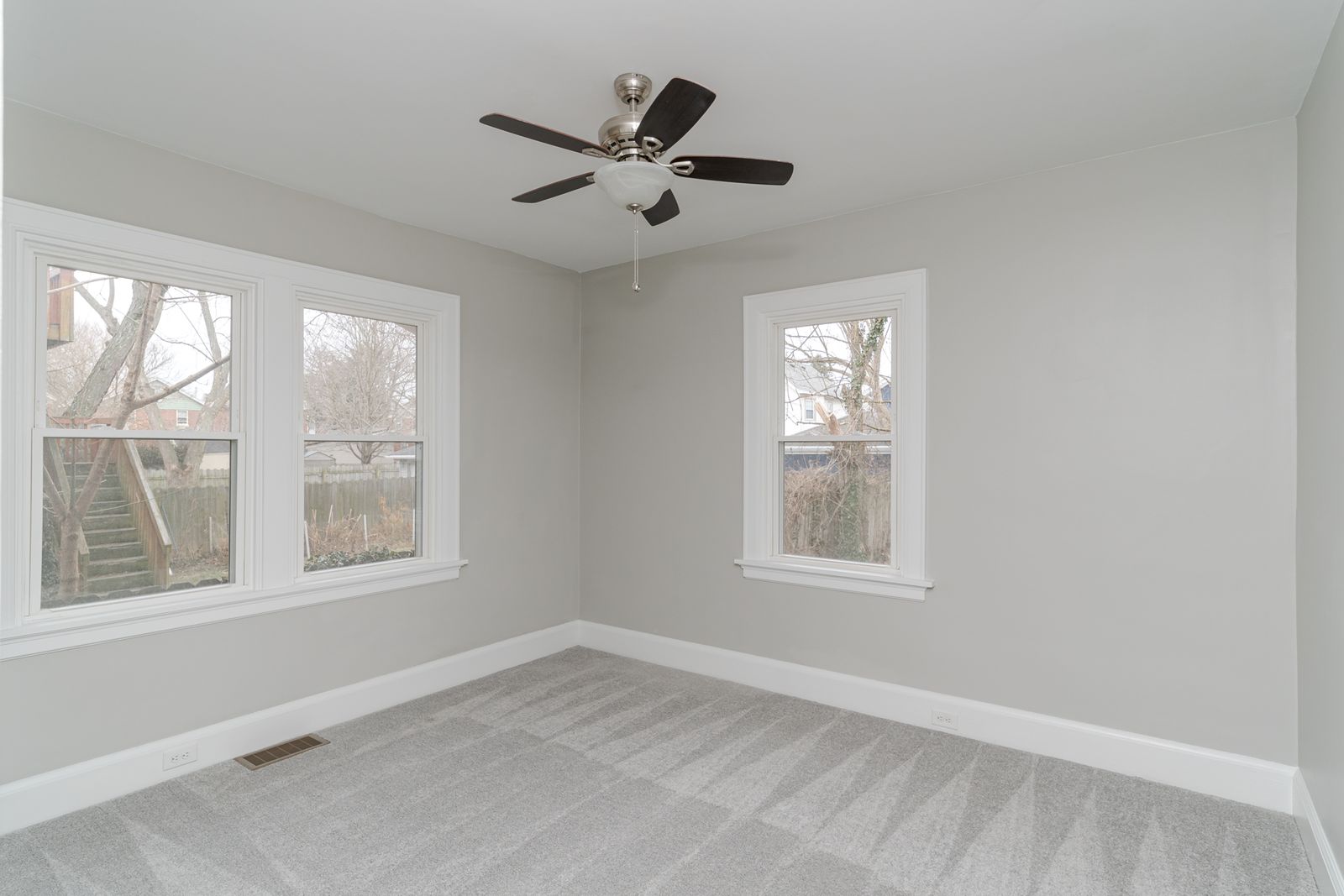 Main-floor bedroom with new carpet, a ceiling fan, and large windows with fresh white trim
