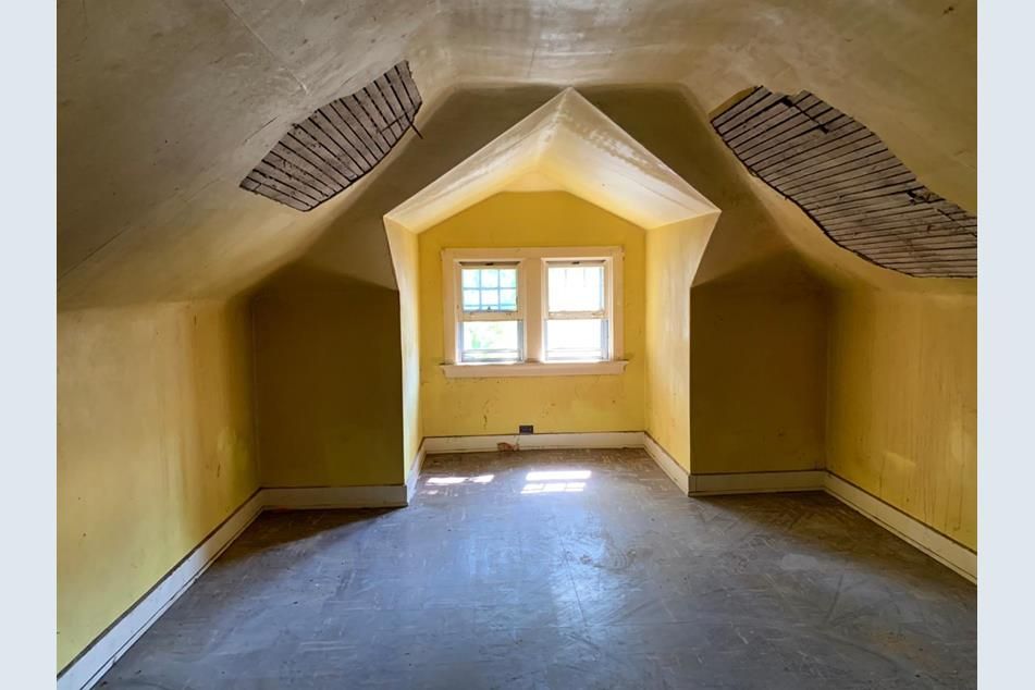 Attic before renovation, with yellowed walls, exposed ceiling lath, and a dull dormer alcove