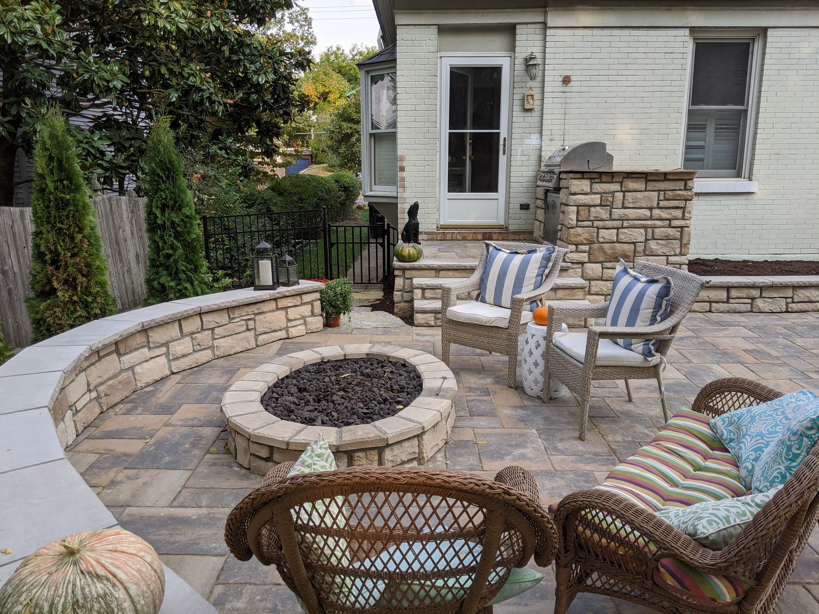 Circular paver patio with a stone fire pit and curved seat wall