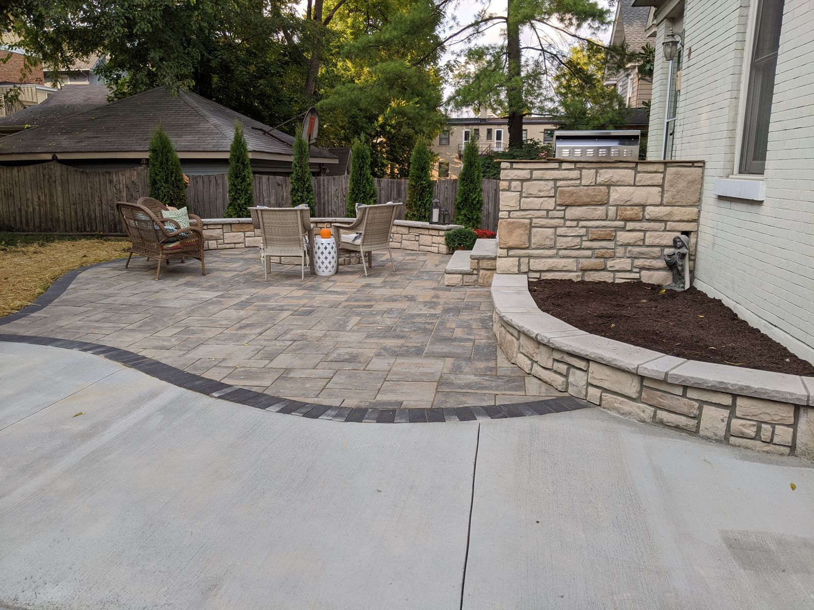 Paver patio with a curved stone seat wall and built-in grill