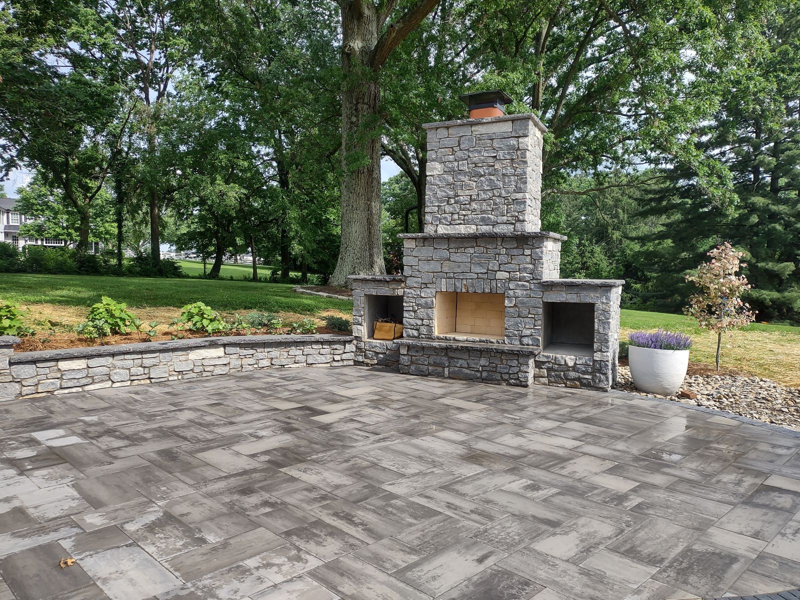 Paver patio with an outdoor stone fireplace and seating