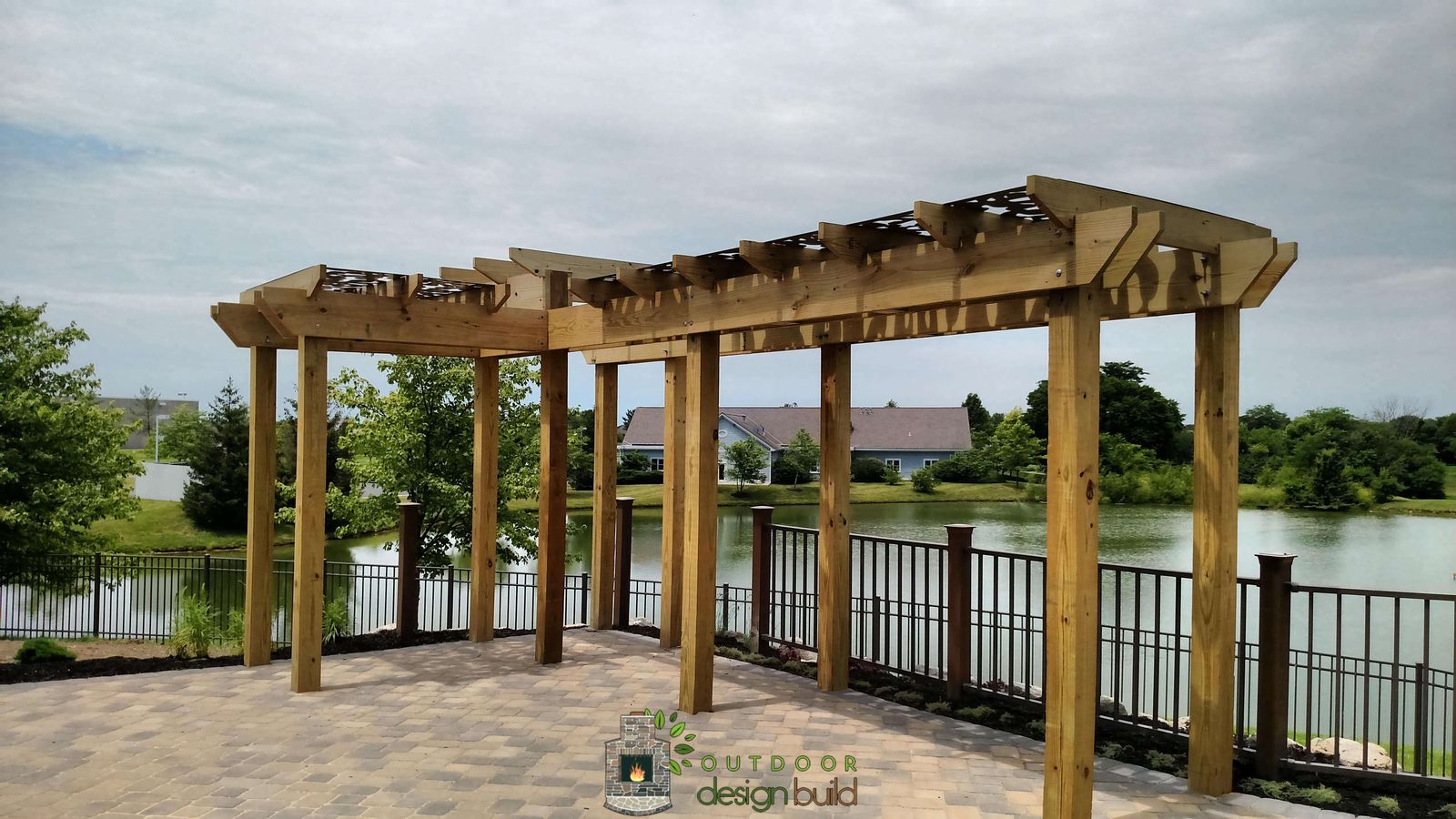 Open-beam pergola over a paver patio near the water