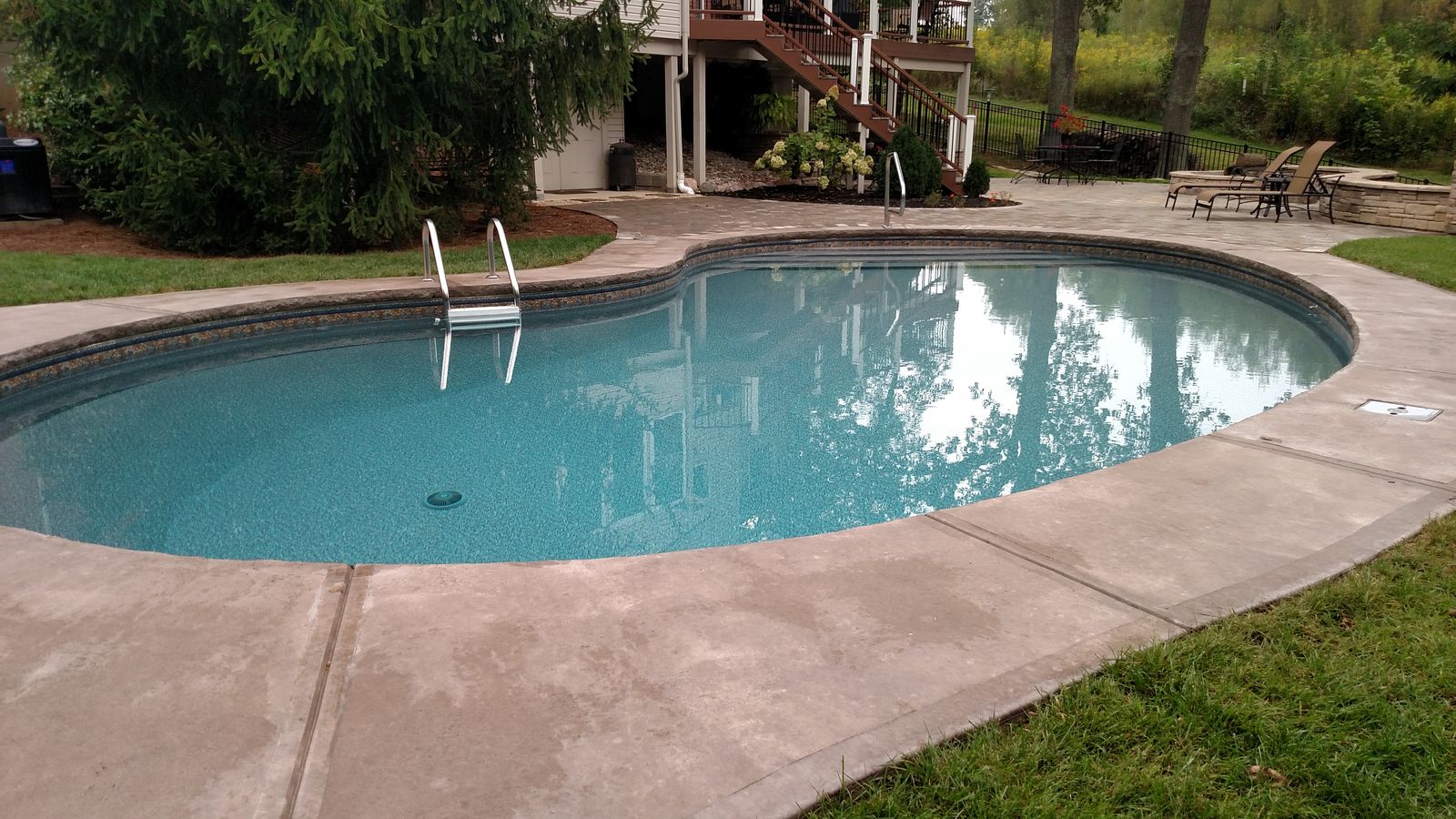 Freeform swimming pool with a paver deck and lounge seating