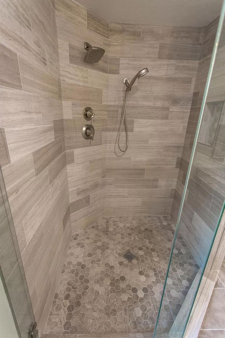 Walk-in shower with stacked stone-look tile and glass panel