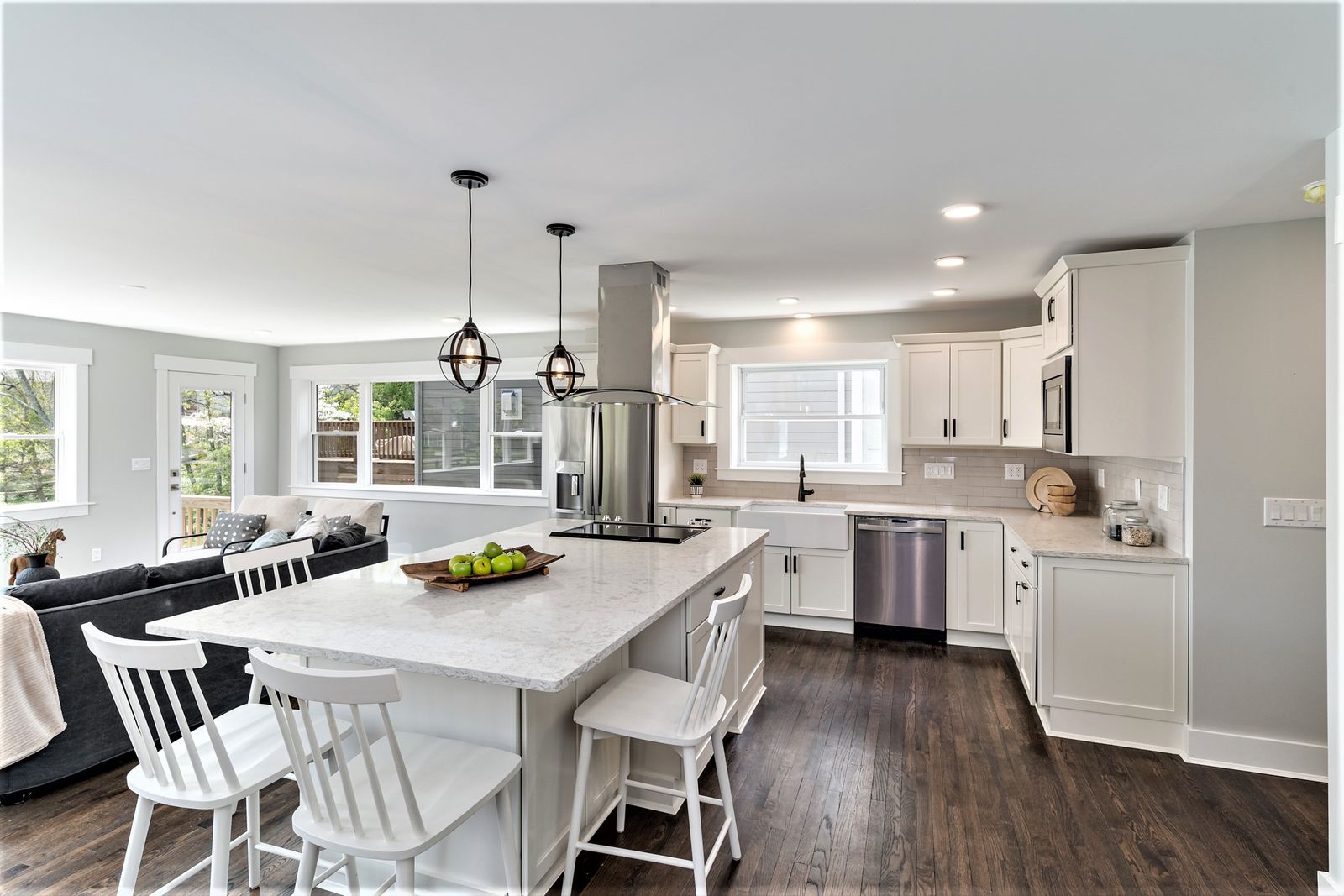 White kitchen with island seating, globe pendant lights, and stainless appliances