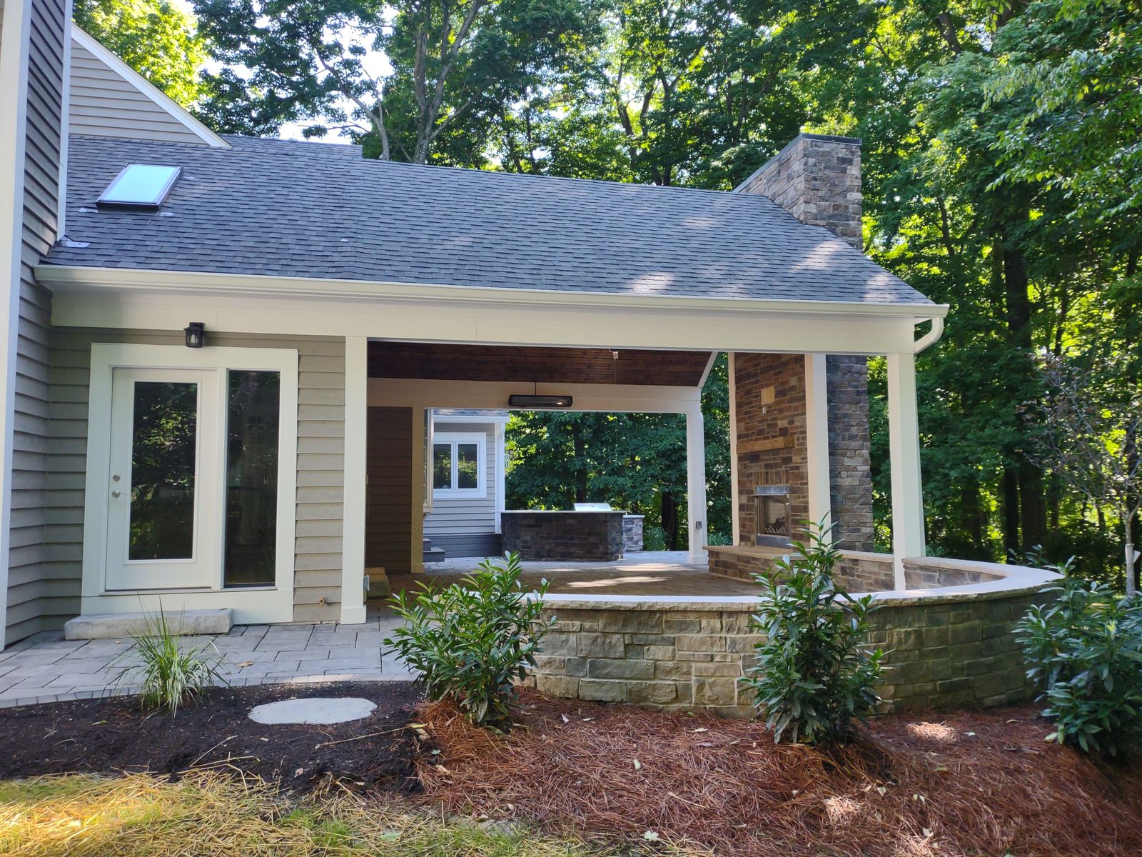 Gabled covered porch with outdoor fireplace and curved stone seat wall
