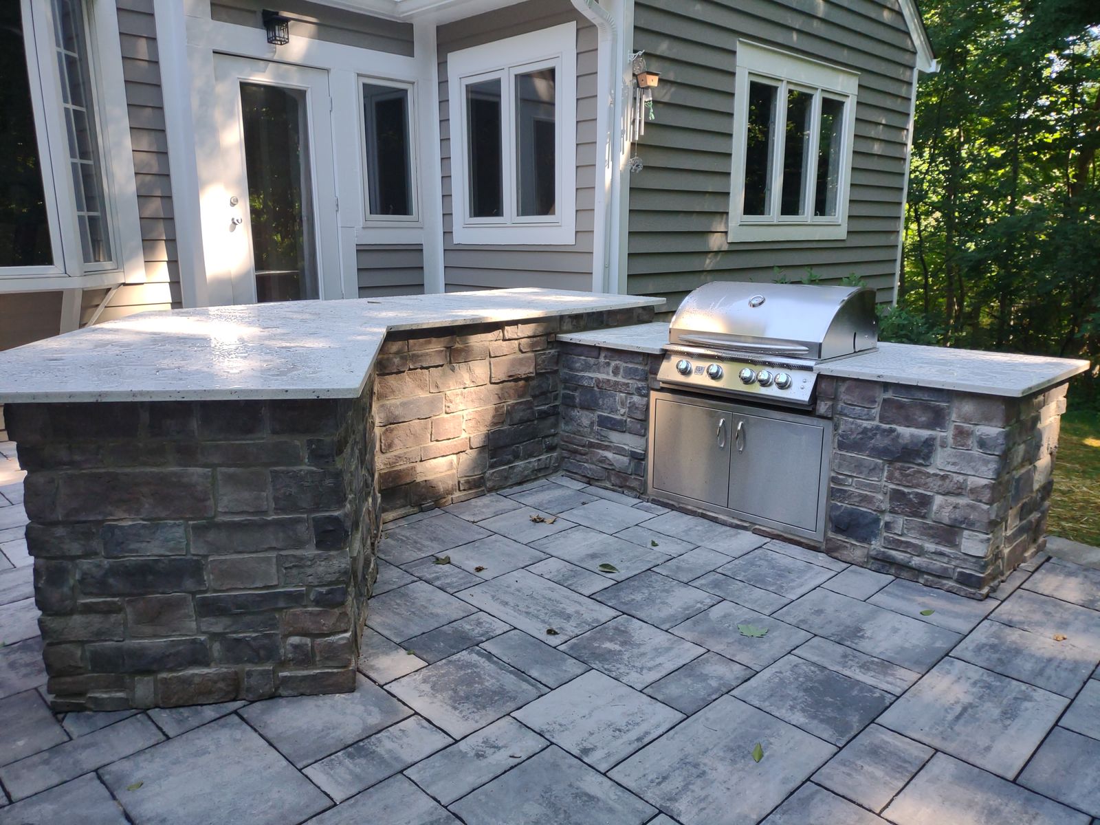 Built-in grill island with stone veneer on paver patio