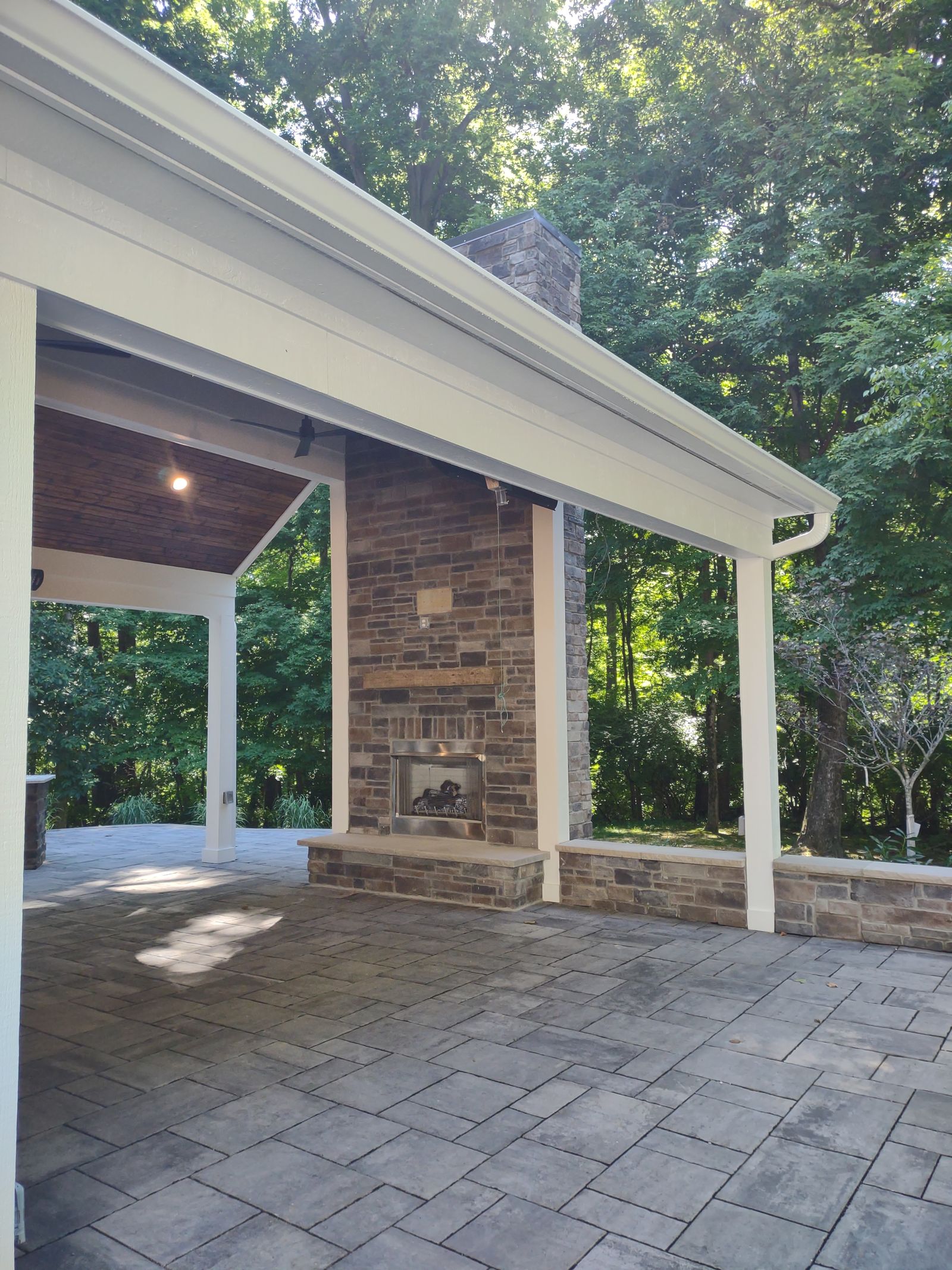 Stone fireplace with raised hearth on covered paver porch