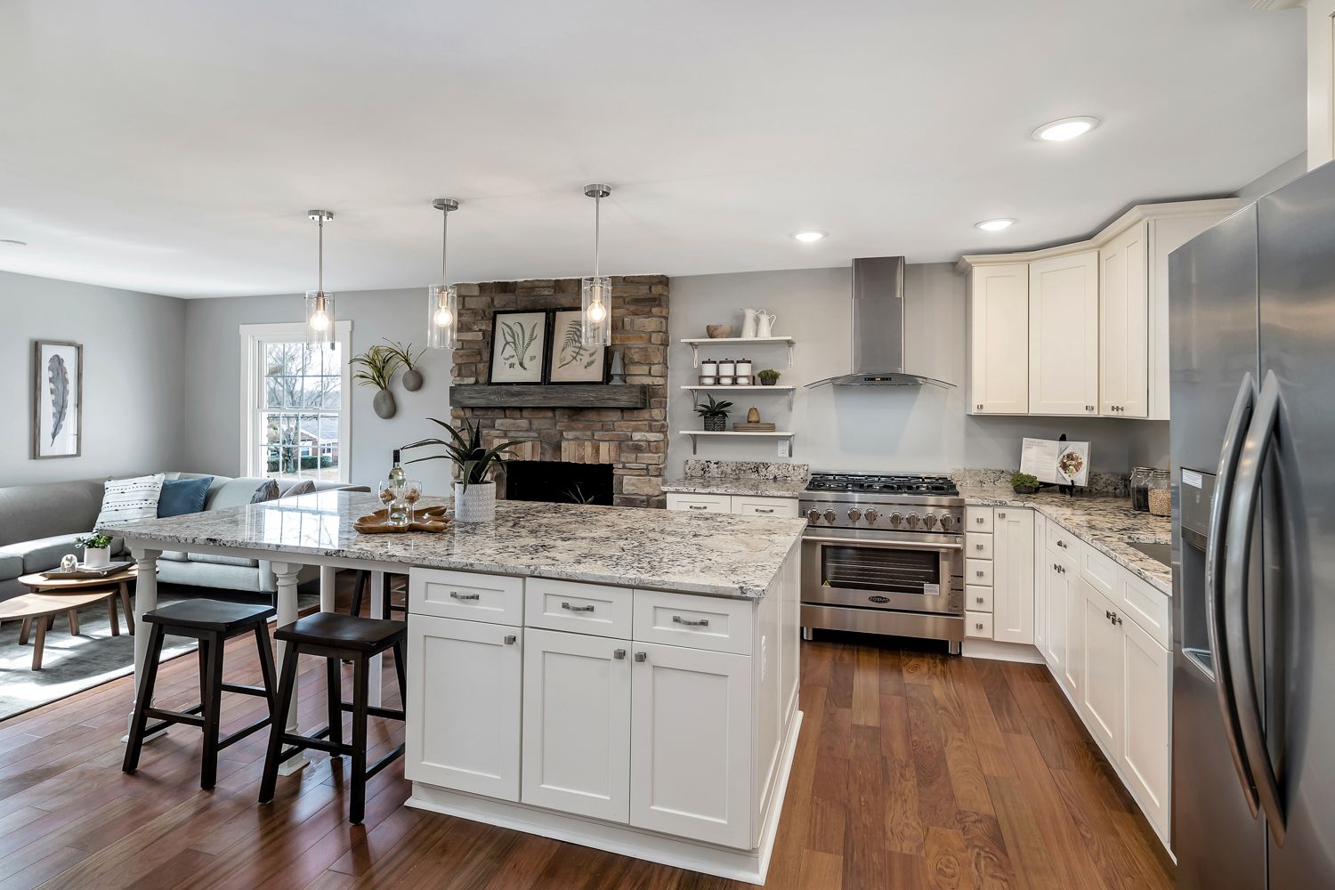 Renovated kitchen with white cabinetry, island seating, and hardwood floors