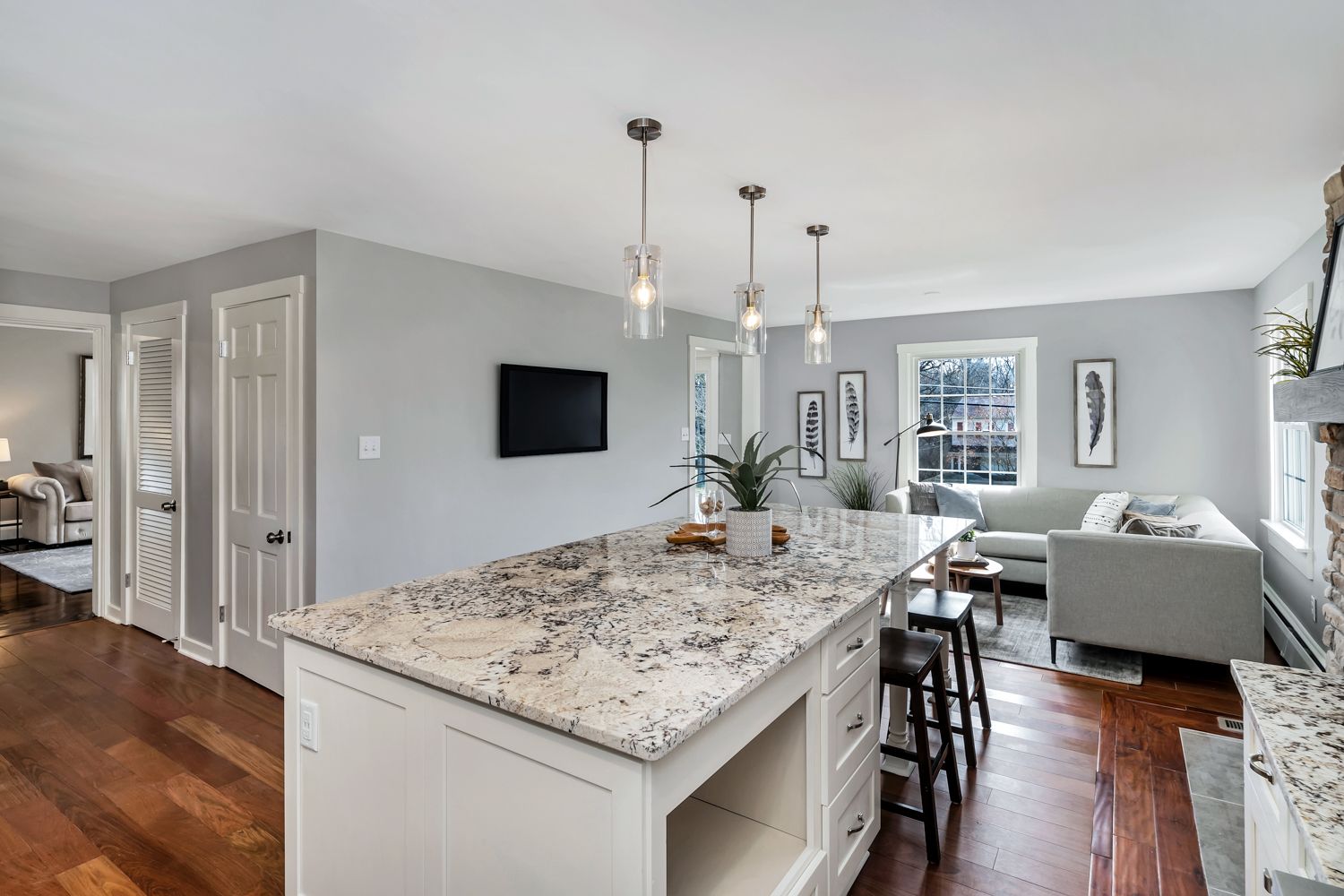 Kitchen island with pendant lighting and view into the family room