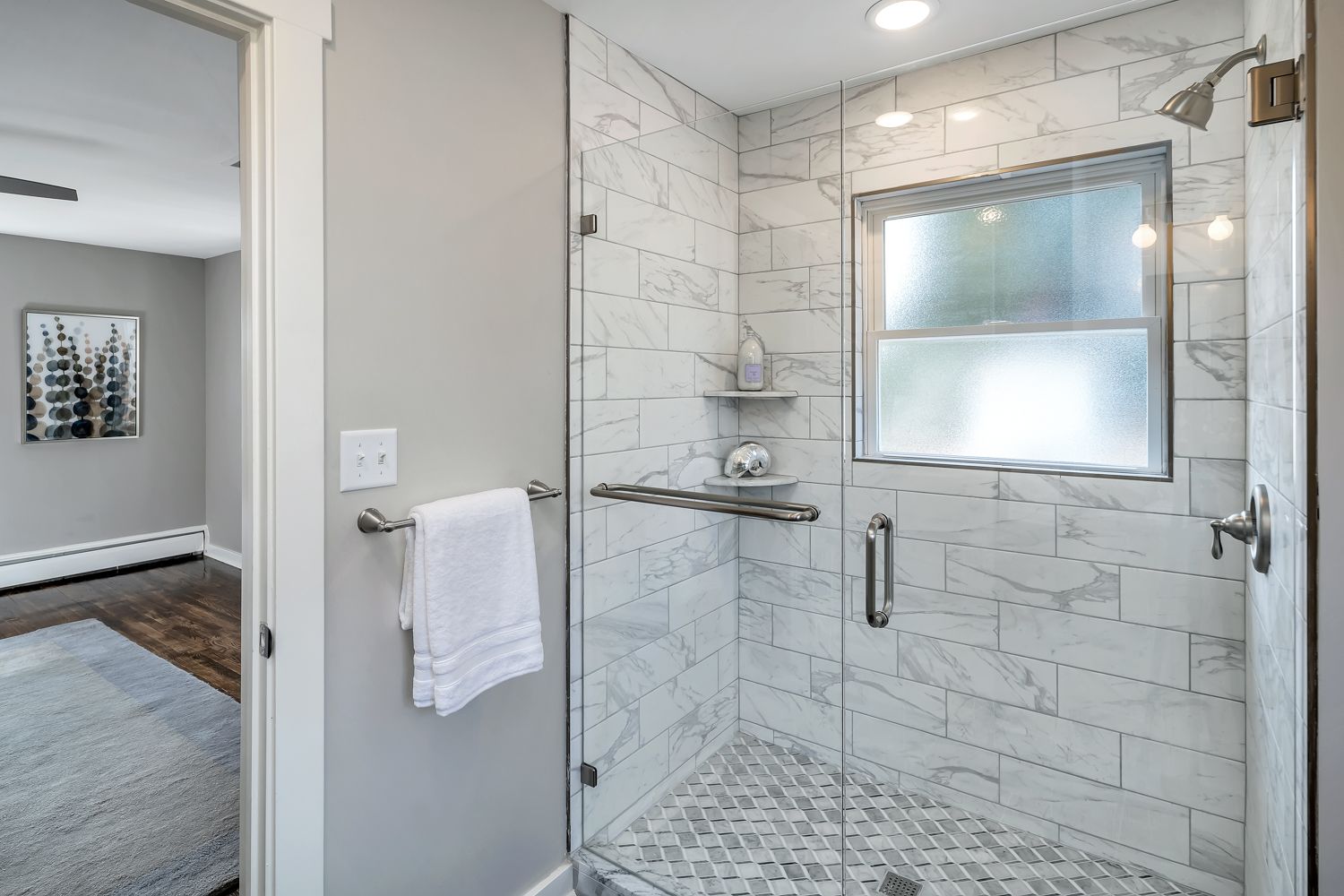 Walk-in shower with marble-look tile and glass enclosure