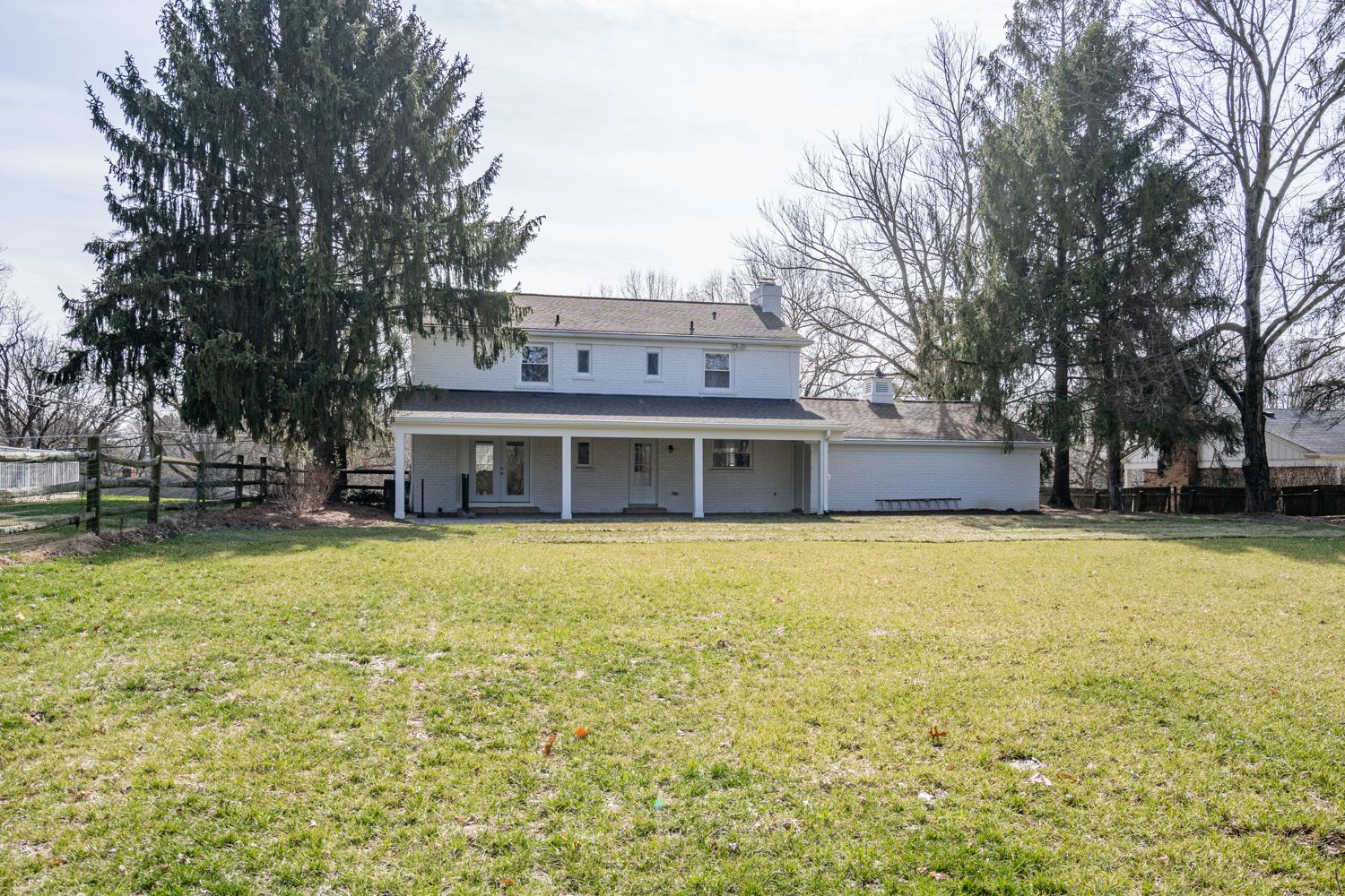 Rear elevation of white-painted brick colonial with covered porch